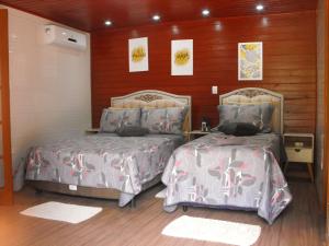 a bedroom with two beds and wooden walls at Pousada Cascata dos Amores in Teresópolis