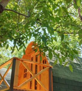 Un edificio naranja con una puerta de madera bajo un árbol en Cabañas Peñaflor Glamping, en Peñaflor