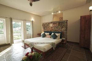 a bedroom with a large bed with a stone headboard at Astroport Sariska "Treetop" by Eight Continents in Tehla
