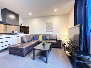uma sala de estar com um sofá de couro e uma televisão em Central CBD One Bedroom Modern Apt Near ChinaTown em Melbourne