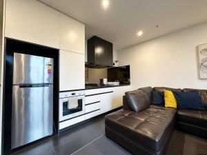 uma sala de estar com um sofá de couro e uma cozinha em Central CBD One Bedroom Modern Apt Near ChinaTown em Melbourne