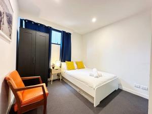 um quarto com uma cama com almofadas amarelas e uma cadeira em Central CBD One Bedroom Modern Apt Near ChinaTown em Melbourne