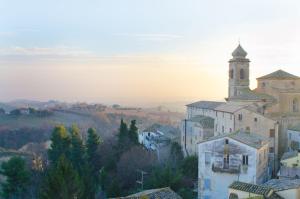 una chiesa con una torre in cima a una città di Dimora nel borgo a Offida