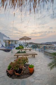 a patio with two benches and potted plants at George & Irene Hotel in Ios Chora