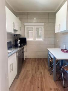 a kitchen with white cabinets and a wooden floor at Eira do Cajado 