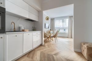 a kitchen with white cabinets and a dining room at Apartament Gold LUX AIRCON in Szczecin