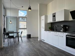 eine Küche mit weißen Schränken und einem Tisch mit Stühlen in der Unterkunft Apartmenthaus Sassnitz Zum Stadthafen Apartment 2 in Sassnitz