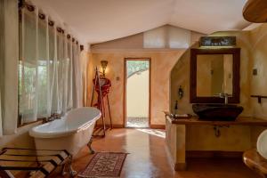 a bathroom with a tub and a sink and a mirror at PrideInn Mara Camp & Cottages in Talek