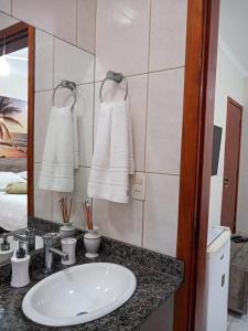 a bathroom with a sink and a mirror and towels at Refúgio BEM-TE-VI in Guarujá