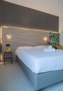 a bedroom with a large white bed with a headboard at Hub Hotel in Gubbio