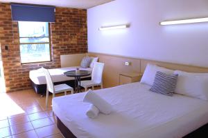 a bedroom with a bed and a table with chairs at Camden Motor Inn in Gold Coast