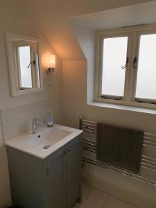 a bathroom with a sink and two windows at The Studio in Ashton Keynes