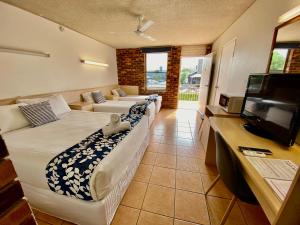 sala de estar con 2 camas y TV de pantalla plana en Camden Motor Inn, en Gold Coast