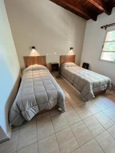 a bedroom with two beds and a tile floor at Hospedaje Los Ilustres in Tunuyán +17 photos
