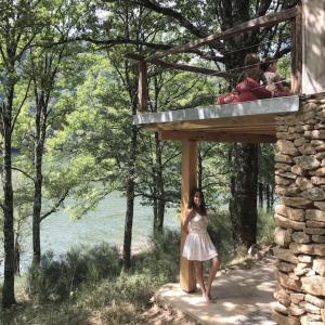 a woman in a white dress standing under a building at Lake House I // Alauzet Ecolodge + Nature spa in Castelnau-de-Mandailles