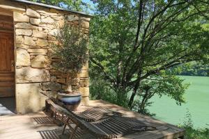 une terrasse en bois avec un banc et une plante en pot dans l'établissement Lake House I // Alauzet Ecolodge + Nature spa, à Castelnau-de-Mandailles
