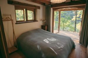 a bedroom with a bed and a large window at Lake House I // Alauzet Ecolodge + Nature spa in Castelnau-de-Mandailles