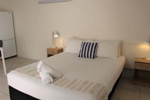 1 dormitorio con 1 cama grande con sábanas y almohadas blancas en Camden Motor Inn, en Gold Coast