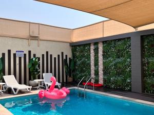 a pool with a pink inflatable swan in the middle at Pool Villa Saraya in Ras al Khaimah
