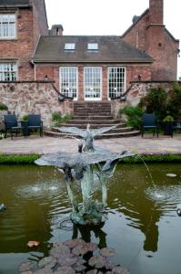 une fontaine dans un étang en face d'un bâtiment dans l'établissement Dunsley Hall Hotel, à Stourbridge