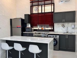 a kitchen with black cabinets and white stools at Pool Villa Saraya in Ras al Khaimah