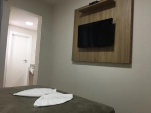 uma cama com duas almofadas e uma televisão na parede em Hotel Paris em Curitibanos
