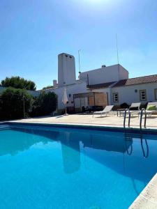 a large blue swimming pool with chairs and a building at Casa das Clarinhas in Monforte