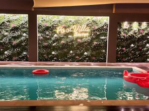 una piscina con dos frisbees rojos frente a un jardín de flores en Pool Villa Saraya, en Ras al Khaimah