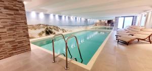 a swimming pool with chairs and a wall with a mural at Hotel Sylter Blaumuschel in Westerland