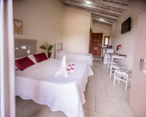 um quarto com 2 camas, uma mesa e cadeiras em Pousada do Mica em Praia do Rosa