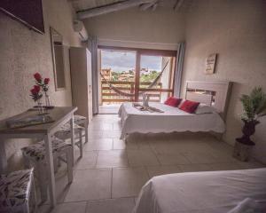Cette chambre comprend 2 lits, une table et une fenêtre. dans l'établissement Pousada do Mica, à Praia do Rosa