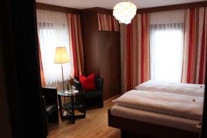 a bedroom with a bed and a chair and a lamp at Pension Wolfgangsee in St. Wolfgang