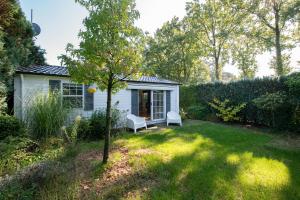 a small house with two white chairs in a yard at 84, gelegen in het rustige & bosrijke Oisterwijk! Met privétuin in Oisterwijk