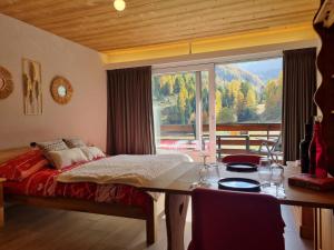 a bedroom with a bed and a table and a large window at Magnifique studio rénové au coeur des 4 Vallées in Nendaz