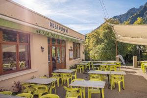 a row of tables and yellow chairs outside of a restaurant at Logis Hôtel Au Gai Soleil du Mont-Aiguille in Chichilianne