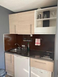kuchnia z drewnianymi szafkami i zlewem w obiekcie Appartement 4pers rénové aux Menuires w Les Menuires