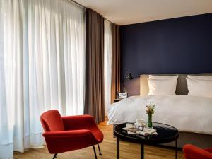 a bedroom with a bed and a red chair and a table at Boston Apartments HH in Hamburg