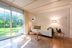 a living room with a white couch and a large window at 84, gelegen in het rustige & bosrijke Oisterwijk! Met privétuin in Oisterwijk