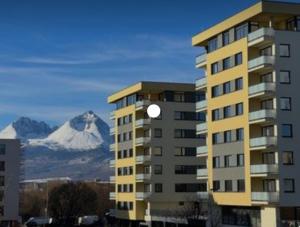 a building with a snow covered mountain in the background at MBV28 Apartments in Poprad
