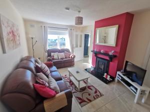 a living room with a leather couch and a fireplace at Molly's Cottage Lahinch in Lahinch