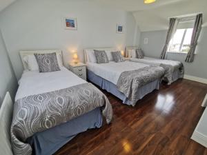 a bedroom with two beds and a wooden floor at Molly's Cottage Lahinch in Lahinch