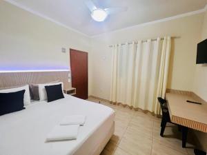 a bedroom with a large white bed and a desk at HOTEL ARLEN 2 in Pouso Alegre