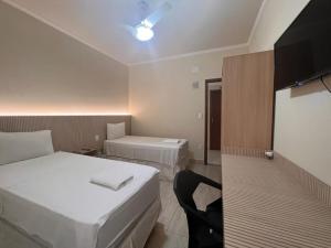 a hotel room with two beds and a tv at HOTEL ARLEN 2 in Pouso Alegre
