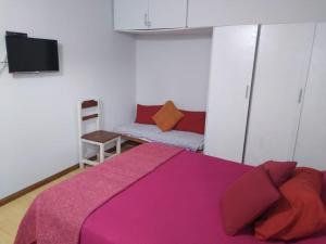 une chambre avec un lit violet et un canapé dans l'établissement Patagonia Beach Las Grutas!, à Las Grutas