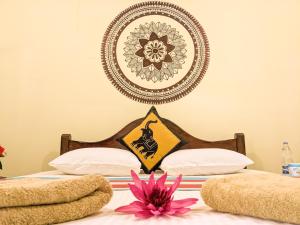 1 dormitorio con 2 camas con una flor rosa en la parte superior en Choona Lodge 'view of sigiriya & pidurangala with sunrise', en Sigiriya