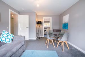 een woonkamer met een bank en een tafel en stoelen bij Monicas Apartment Lovely ground floor 2 bedroom serviced apartment in Coatbridge