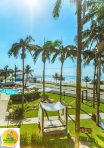 uma vista para um parque com palmeiras e o oceano em Hotel Villareal Guaratuba - Caieiras em Guaratuba