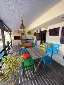 una terraza con mesa de madera y sillas coloridas en Pousada Gruta do Monge, en Bombinhas