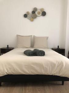 ein Bett mit zwei Kissen und zwei Uhren an der Wand in der Unterkunft Appartement en duplex à Auxonne in Auxonne