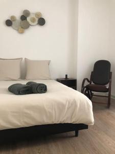 ein Schlafzimmer mit einem Bett mit zwei Kissen und einem Stuhl in der Unterkunft Appartement en duplex à Auxonne in Auxonne